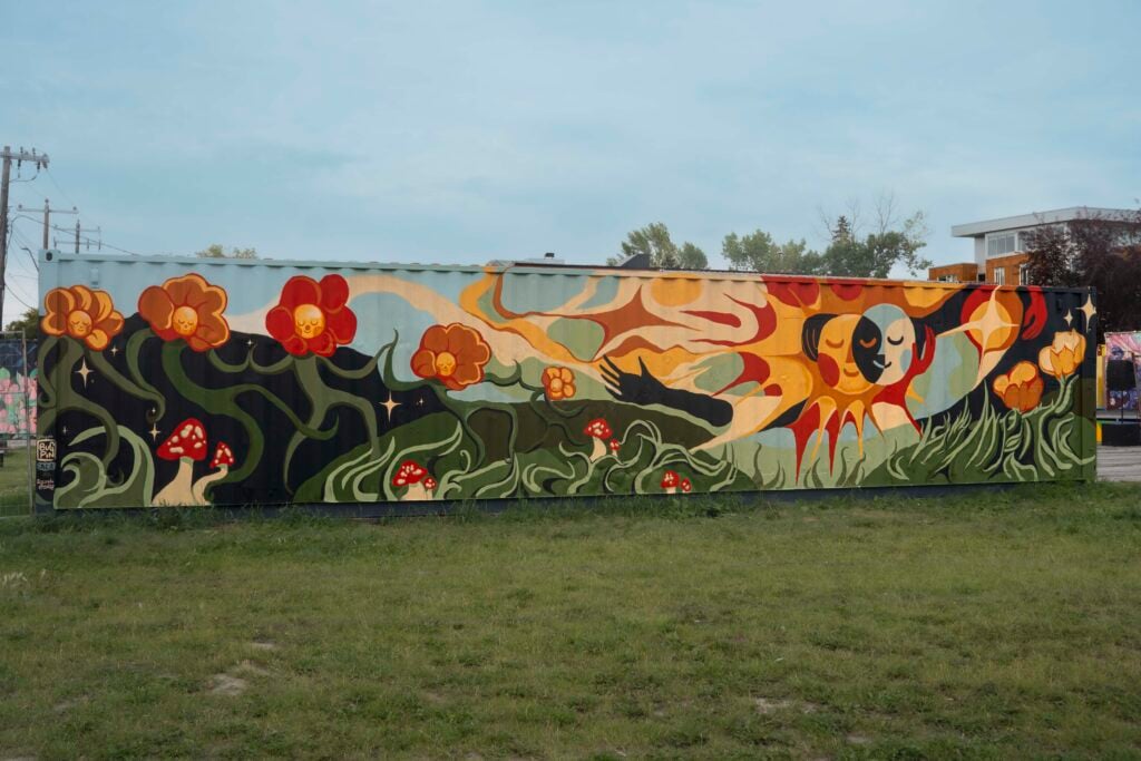 A photograph of a colourful, nature inspired mural titled "How Love Flows" by youth artists Zia, Elizaveta, Asher, Jan, Q