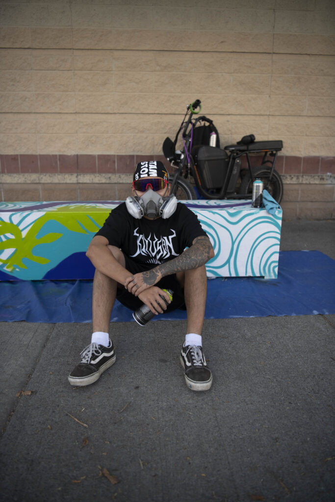 Artist sitting in front of painted bench.