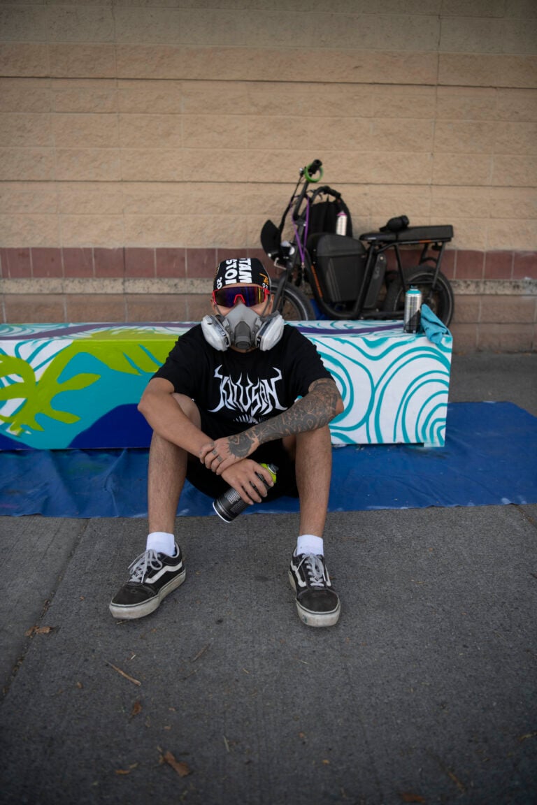 Artist sitting in front of painted bench.